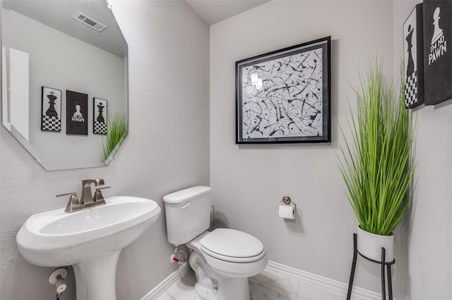 half bath featuring visible vents, marble finish floor, toilet, baseboards, and a sink