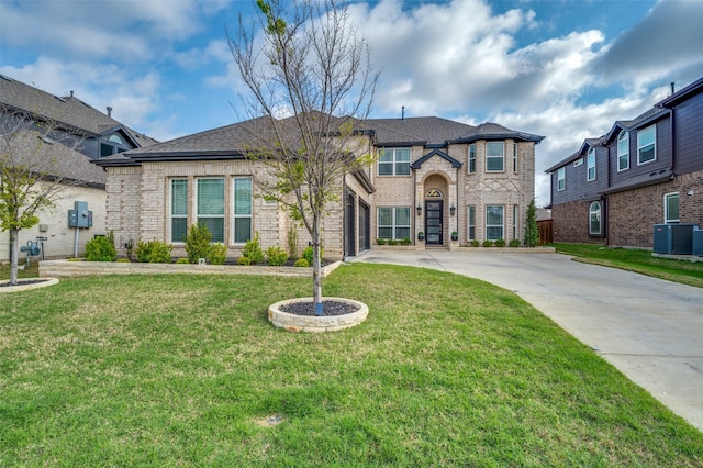 french country home featuring driveway, central AC unit, a garage, brick siding, and a front lawn