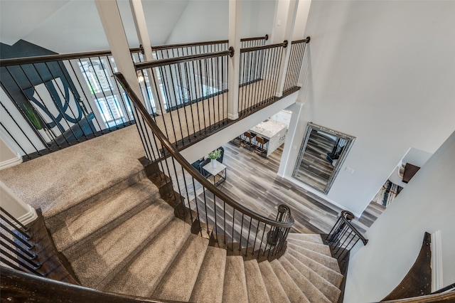stairway with a high ceiling and wood finished floors