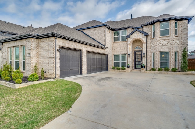 french country style house featuring driveway, brick siding, a front lawn, an attached garage, and a shingled roof