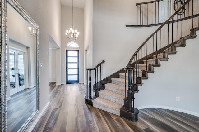 entryway with wood finished floors, stairs, a high ceiling, and a notable chandelier