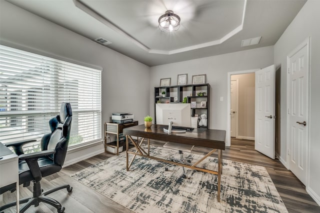 home office featuring a tray ceiling, dark wood-style flooring, and visible vents