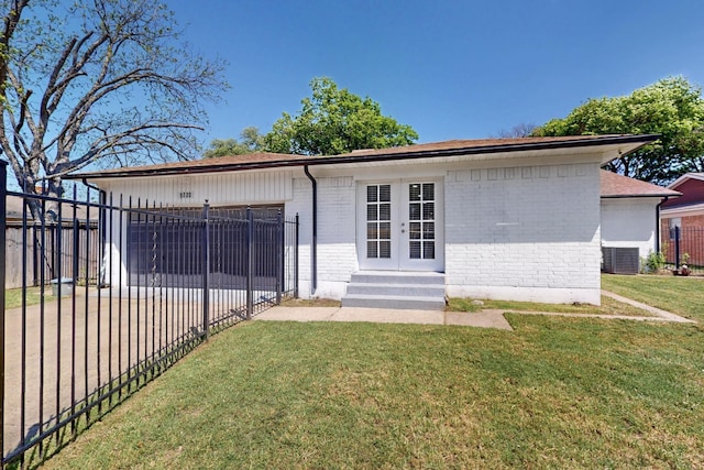 rear view of house with french doors, brick siding, fence private yard, a lawn, and entry steps