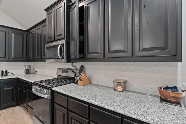 kitchen featuring vaulted ceiling, tasteful backsplash, appliances with stainless steel finishes, and dark cabinets