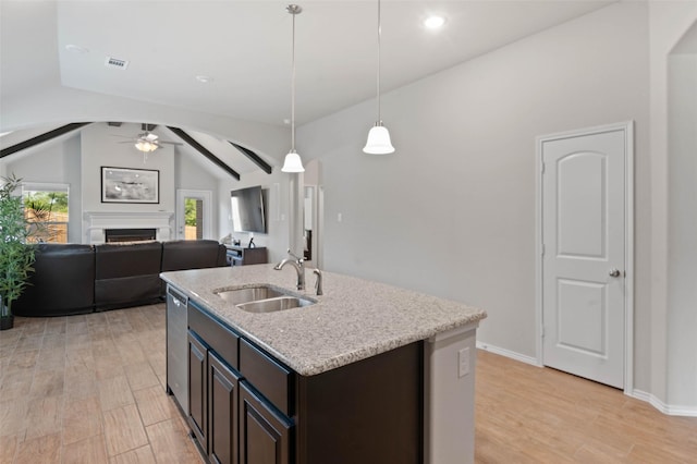 kitchen featuring light wood finished floors, a sink, vaulted ceiling, a ceiling fan, and a fireplace
