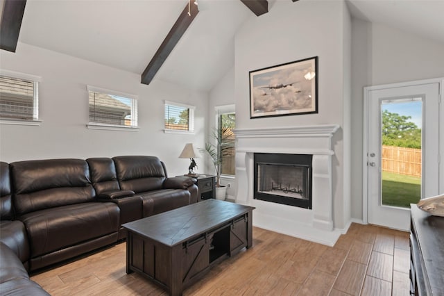 living area featuring a fireplace, light wood-style flooring, lofted ceiling with beams, and plenty of natural light