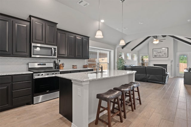 kitchen featuring lofted ceiling, stainless steel appliances, visible vents, a sink, and light wood-style flooring