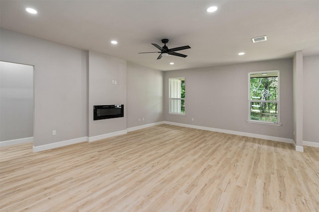 208 Splitrail Dr, Mabank, TX 75143 - unfurnished living room featuring baseboards, a glass covered fireplace, recessed lighting, and light wood-style floors