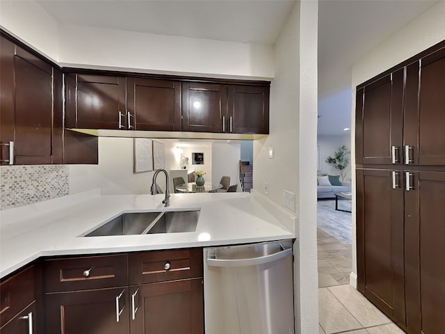 kitchen featuring stainless steel dishwasher, dark brown cabinets, a sink, light countertops, and backsplash
