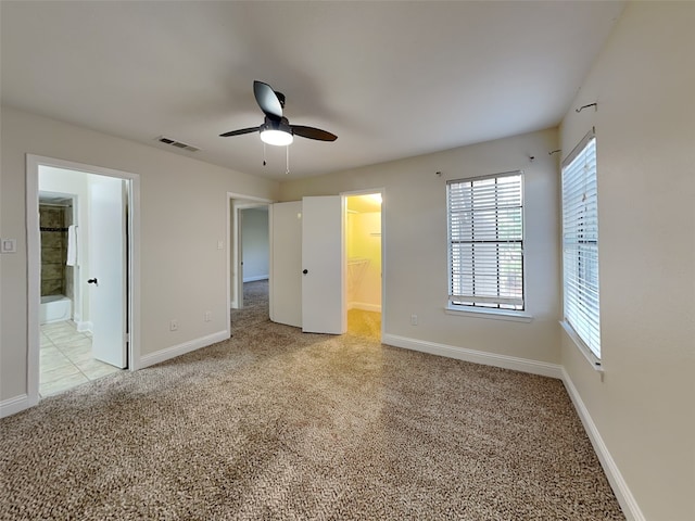 unfurnished bedroom with baseboards, visible vents, a spacious closet, and light colored carpet