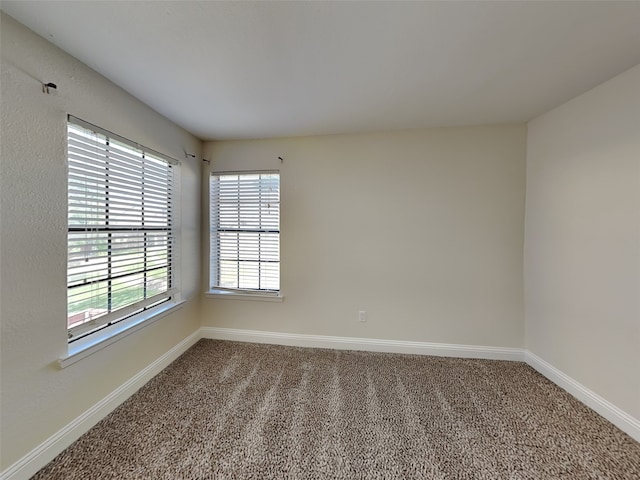 unfurnished room featuring carpet and baseboards