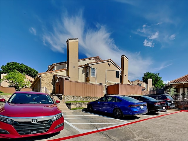 view of front of house with a residential view, a chimney, and uncovered parking