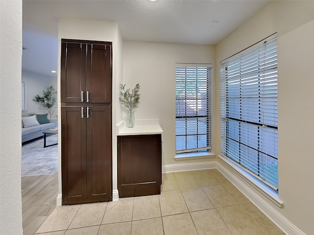 interior space featuring baseboards, dark brown cabinetry, and light tile patterned flooring