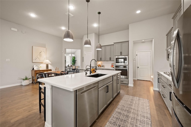 11721 Bull Creek Dr, Northlake, TX 76226 - kitchen with appliances with stainless steel finishes, gray cabinetry, a kitchen bar, wood finished floors, and recessed lighting