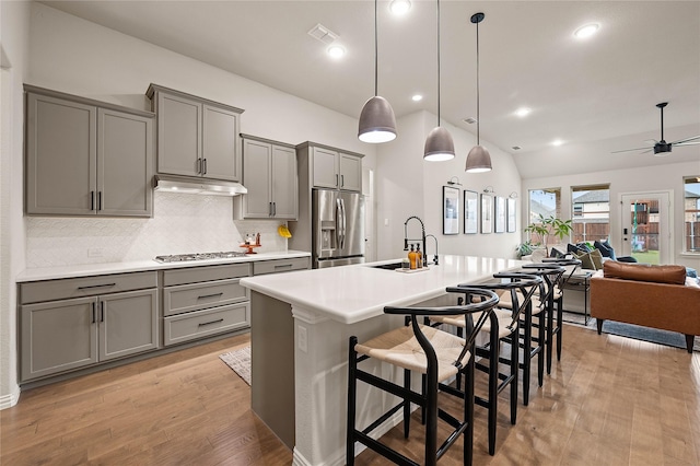 11721 Bull Creek Dr, Northlake, TX 76226 - kitchen with stainless steel fridge with ice dispenser, gray cabinetry, tasteful backsplash, open floor plan, and light wood-style floors