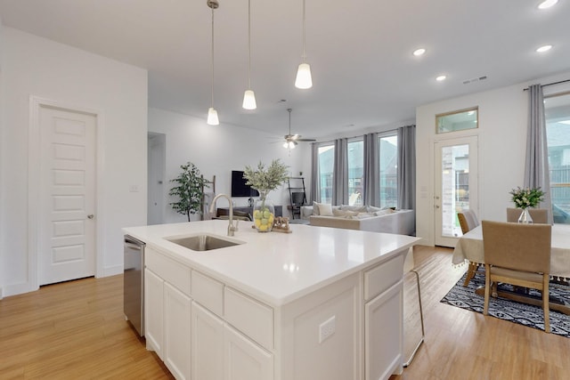 kitchen with stainless steel dishwasher, light wood finished floors, recessed lighting, and a sink
