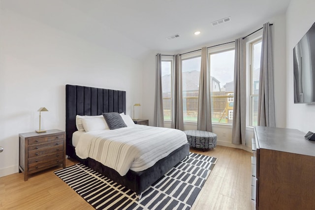 bedroom with visible vents, multiple windows, and light wood-style flooring