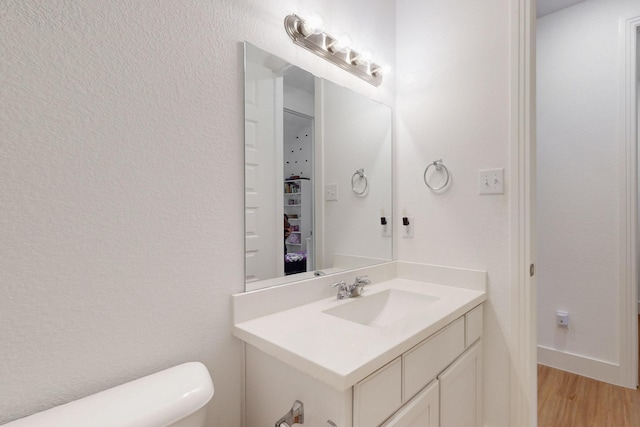 bathroom featuring wood finished floors, toilet, and vanity