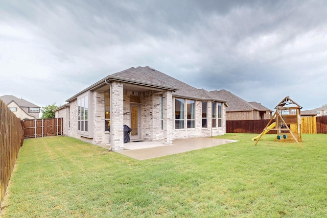 rear view of house featuring a fenced backyard, a yard, brick siding, a shingled roof, and a patio