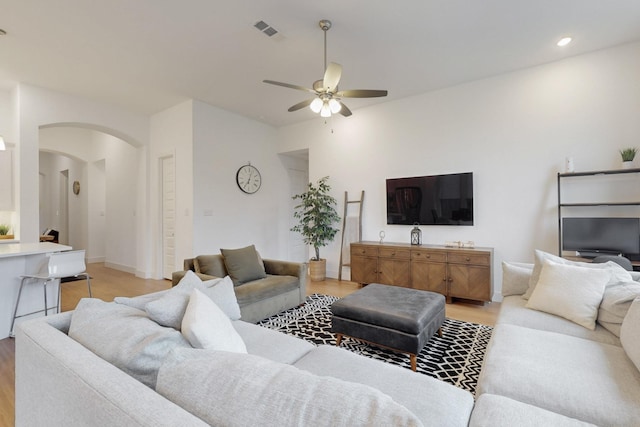 living area featuring recessed lighting, arched walkways, light wood finished floors, visible vents, and a ceiling fan