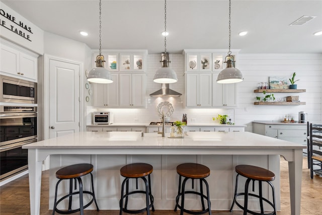 kitchen featuring white cabinets, stainless steel appliances, a kitchen breakfast bar, and visible vents