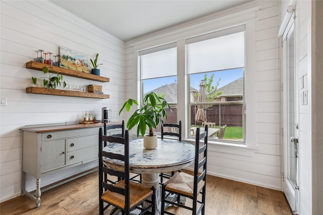 dining area with light wood finished floors, baseboards, and wood walls