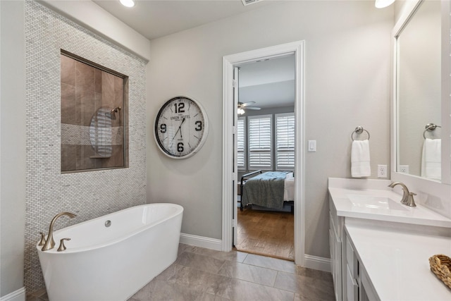 bathroom with vanity, baseboards, a freestanding tub, tiled shower, and ceiling fan
