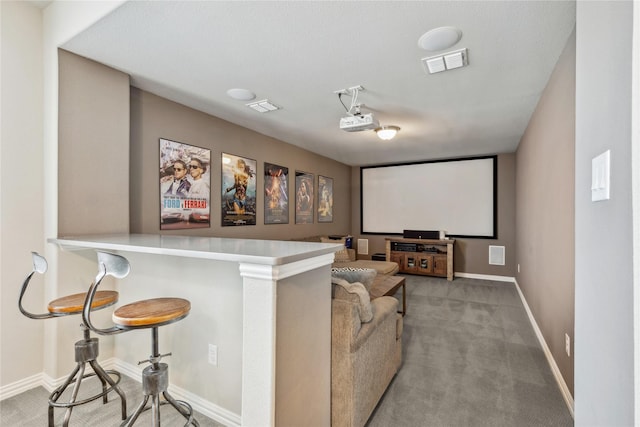 home theater room featuring baseboards, visible vents, and light colored carpet