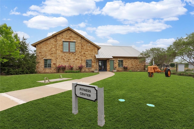 traditional home featuring fence, a front yard, and metal roof