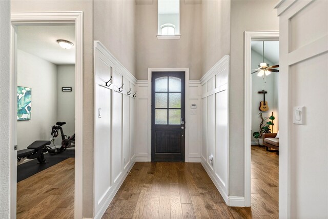 mudroom with wood finished floors, a towering ceiling, ceiling fan, and a decorative wall
