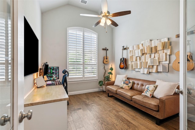 home office featuring baseboards, visible vents, lofted ceiling, wood finished floors, and ceiling fan