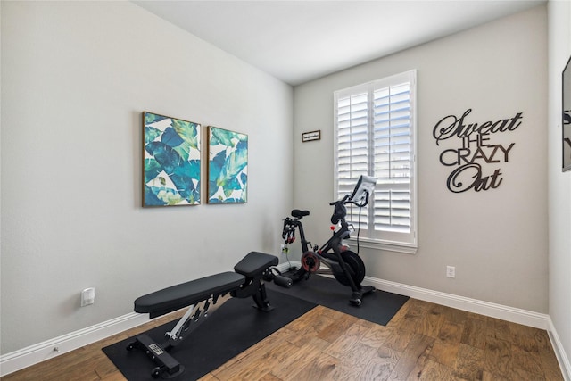 exercise area with wood finished floors, a healthy amount of sunlight, and baseboards