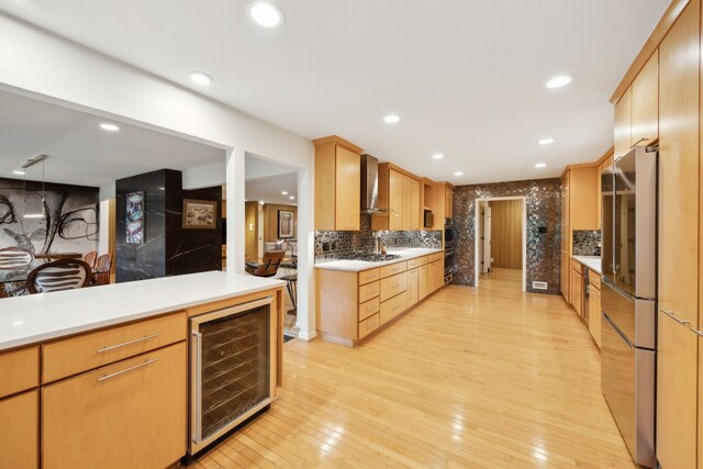 kitchen with beverage cooler, light wood finished floors, smart refrigerator, wall chimney exhaust hood, and tasteful backsplash