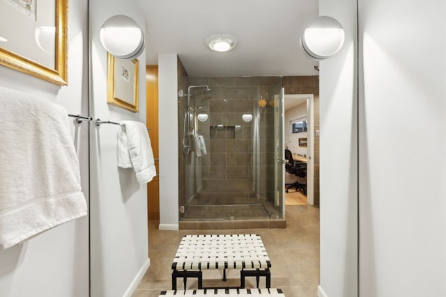 bathroom featuring baseboards, tile patterned flooring, and a shower stall