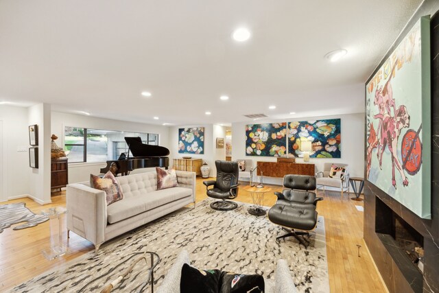living room with recessed lighting, visible vents, light wood finished floors, and a large fireplace
