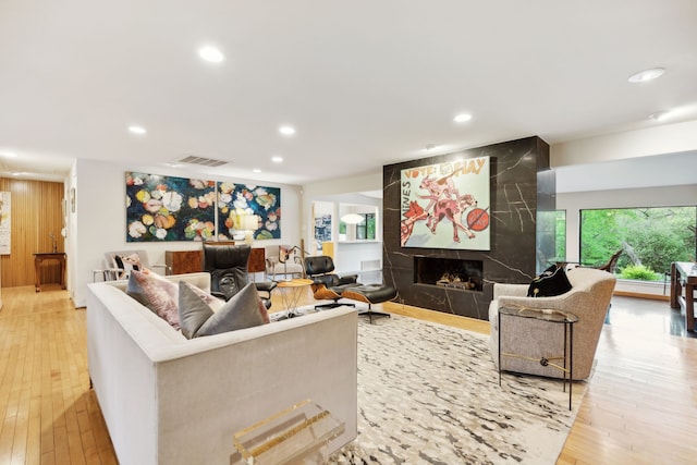 living area featuring recessed lighting, a high end fireplace, hardwood / wood-style floors, and visible vents