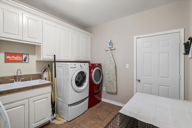 laundry room with a sink, independent washer and dryer, dark tile patterned floors, baseboards, and cabinet space