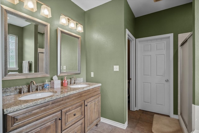 bathroom featuring baseboards, a sink, a shower stall, and double vanity