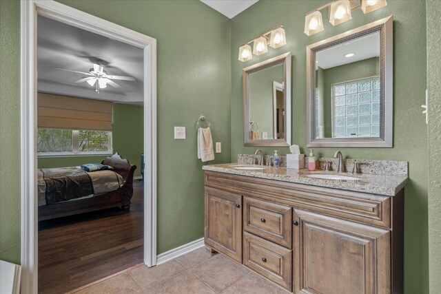 full bathroom with double vanity, connected bathroom, baseboards, and a sink