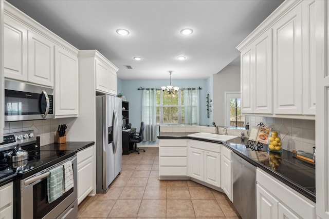kitchen with dark countertops, tasteful backsplash, a sink, appliances with stainless steel finishes, and a notable chandelier