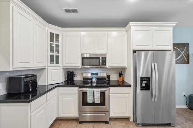 kitchen with tasteful backsplash, dark countertops, visible vents, white cabinetry, and appliances with stainless steel finishes