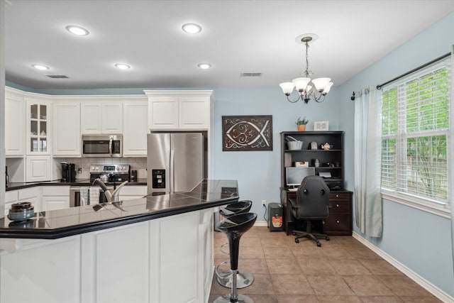 kitchen featuring baseboards, appliances with stainless steel finishes, a breakfast bar, and an inviting chandelier
