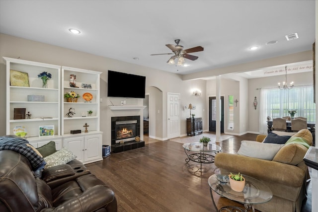 living room with ceiling fan with notable chandelier, a tile fireplace, visible vents, dark wood-style floors, and recessed lighting