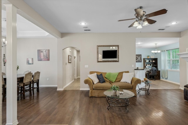 living area featuring visible vents, arched walkways, wood-type flooring, baseboards, and ceiling fan with notable chandelier