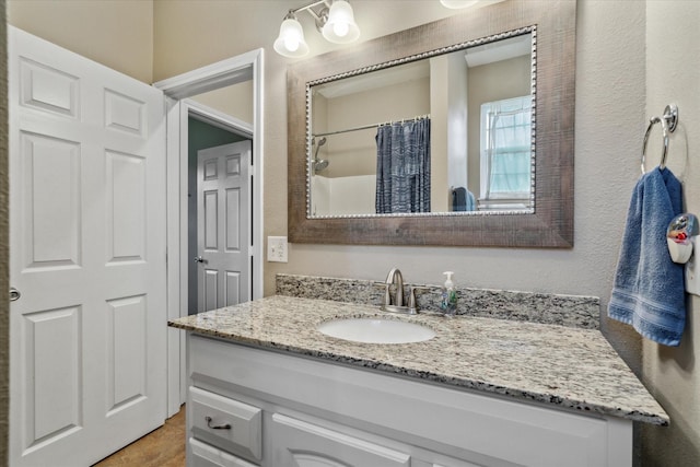 bathroom featuring a shower with curtain, a textured wall, and vanity