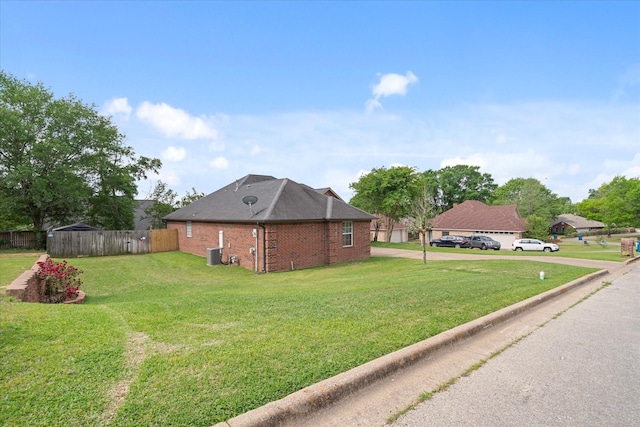 view of side of home with central AC unit, fence, concrete driveway, a lawn, and brick siding