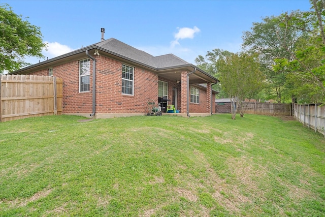 rear view of house featuring brick siding, a lawn, and a fenced backyard