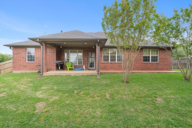 back of house featuring brick siding, a yard, a patio area, and fence