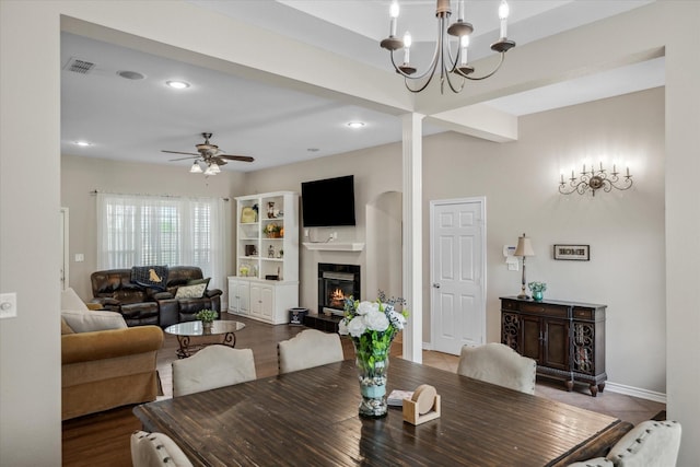 dining room featuring baseboards, visible vents, a glass covered fireplace, recessed lighting, and ceiling fan with notable chandelier