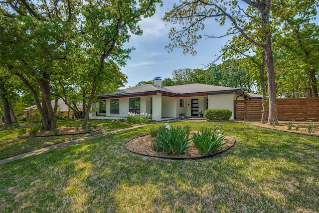 rear view of house with a yard, a chimney, and fence